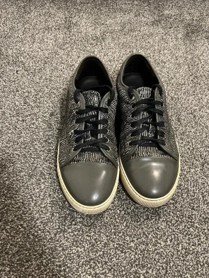 Lanvin Sneakers – Svart/Vit, Storlek 42-43 - Snygga svarta sneakers från Lanvin med stickad ovandel och vita detaljer på sulan. Tåpartiet är i blankare material och skorna har svarta skosnören. Zebra-liknande mönster gör dem riktigt unika.  Perfekta för dig som gillar en stilren och modern look – passar lika bra till jeans som streetwear.  Skick: Bra, lite små heeldrag och ett litet märke (knappt synligt på bild). Pris 1899kr! Storlek: 42-43