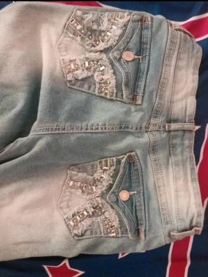 Low rise jeans with rhinestones  - Säljer bootcut jeans som är ljusblåa och har detajierad design på bak fickan