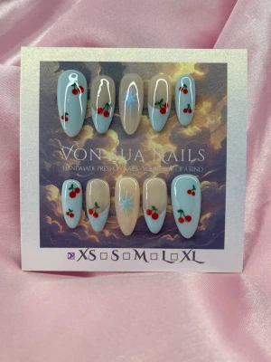 CherryGlow 🍒(XS);Medium Almond - Snygga handgjorda press-on naglar i en medium mandelformad design. Naglarna har en ljusblå och nude bas med körsbär och stjärndetaljer. Perfekt för dig som vill ha en unik och lekfull look. XS: 14 mm, 11 mm, 11,5 mm, 10 mm, 8 mm