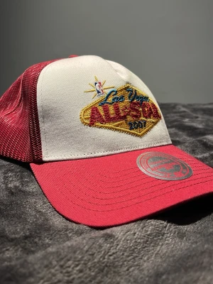 NBA All Star 2007 keps röd/vit - Snygg truckerkeps från Mitchell & Ness med broderad NBA Las Vegas All Star 2007-logga. Kepsen har röd skärm och mesh baktill, samt vit frontpanel. Justerbar passform med snapback. Perfekt för dig som gillar basket och streetwear. 🔥Helt ny!!!🔥
