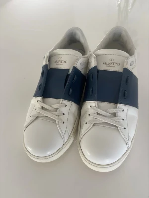 Valentino Garavani vita sneakers - Snygga vita sneakers från Valentino Garavani med den fetaste färgen du kan hitta på Valentinos. Skorna har klassisk låg profil, rund tå och är tillverkade i slätt läder. Perfekta för dig som gillar stilrena och exklusiva sneakers med unik design.
