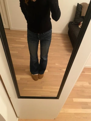 Mörkblå bootcut jeans - Säljer ett par mörkblå bootcut jeans med klassisk femficksmodell och normal midja. Jeansen har en lätt tvättad look och är tillverkade i ett mjukt denimtyg som sitter skönt. Perfekta för dig som gillar en avslappnad men ändå snygg stil.