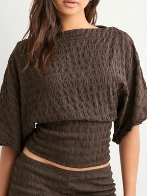 Brun croppad offshoulder t-shirt - Trendig brun croppad t-shirt med offshoulder-design och trekvartsärm. Tillverkad i ett strukturerat, stretchigt material som ger en cool och avslappnad vibe. Perfekt nu mot våren ich sommaren. Tyvärr är denna topp knapp använd🥰