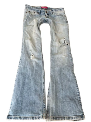 Vintage superlågmidjade bootcut jeans från Levi’s - Sååå sjukt snygga ljusblå superlågmidjade vintage jeans med slitna detaljer från Levis! Står superlowwaist bootcut på lappen i ❤️ Innebenslängd: 84 cm Midjemått rakt över: 38 cm