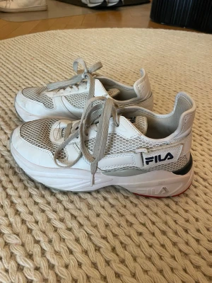 Vita Fila sneakers - Snygga vita sneakers från Fila. De går att göra rent mer. Ovandelen är i en mix av syntet och mesh för extra andningsförmåga. TVEKA INTE OM FRÅGOR!🩷