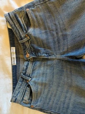 Blå raka/flare jeans från Bershka - Säljer ett par blå jeans från Bershka med rak/flare passform och fem fickor. Jeansen har en ”urtvättad och sliten” blå färg. Några defekter, se bilderna.