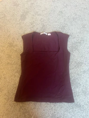 Vinröd topp från Gina tricot  - Snygg vinröd topp med breda axelband och fyrkantig ringning. Tillverkad i mjukt, stretchigt material som sitter skönt mot kroppen. Perfekt att styla med jeans eller kjol för en trendig look💓använd få gånger💓