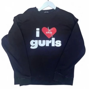Svart sweatshirt med tryck från Callie - Cool svart sweatshirt från Callie med texten 'i ❤️ gurls' på framsidan och '(why are we so sexy)' på ryggen. Tröjan har rund hals, långa ärmar och ribbade muddar. Perfekt för dig som vill sticka ut med ett statement-plagg.
