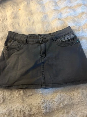 Grå jeanskjol med broderi - Säljer en super fin grå jeanskjol i storlek M! I modellen är kjolen ganska kort och nästan helt rak. Den har mycket små snygga detaljer💗💗