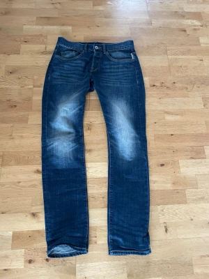 Mörkblå raka jeans med slitningar - Säljer dessa otroliga mörkblå jeans ifrån edc med raka ben och sköna slitningar på låren och knäna. Klassisk femficksmodell med kontrastsömmar och knappgylf. Jeansen har en avslappnad vibe och passar perfekt till en streetwear-look. 