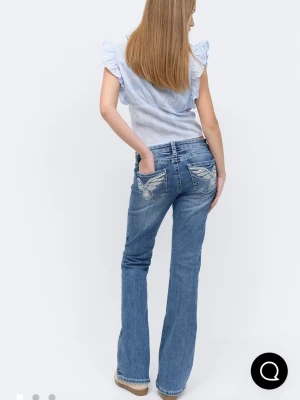 Blå bootcut jeans med broderi - Säljer ett par blå bootcut jeans med snygga broderade detaljer på bakfickorna. Jeansen har en klassisk femficksmodell och är tillverkade i denim med lätt tvättad look. Perfekta för dig som gillar en avslappnad men trendig stil. De har passform kvinna men av nån anledning kan jag bara trycka in man. Storlek: 158