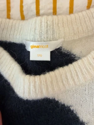 Vit och mörkblå stickad tröja Gina Tricot - Stickad tröja från Gina Tricot i färgerna vit och mörkblå. Tröjan har rund halsringning och är gjord i ett mjukt, fluffigt material som känns riktigt mysigt. Perfekt för kyliga dagar och enkel att matcha med jeans eller kjol.