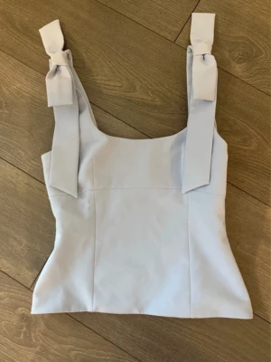 Helt ny blå topp zara - Helt ny blå topp från Zara i strl s, otroligt fin till sommaren, har söta rosettdetaljer vid axlarna🩷