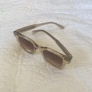 Chimi Solglasögon - Snygga solglasögon från Chimi med transparent beige båge och fyrkantig form. Glasen är tonade i brunt och ger en cool retrovibe. Perfekta för soliga dagar när du vill sticka ut lite extra.