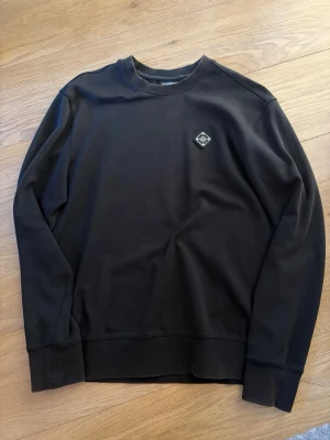 J.Lindeberg tröja - En helt vanlig svart tröja från J.Lindeberg med en metall logga på vänster bröst. Storlek S, bra skick, inga defekter. Lite solblekt på kanterna av tröja. Köpte den för 1400kr för något år sedan, tror inte man kan köpa den längre. Skriv vid frågor!