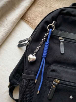 Handgjord Paracord Väskcharm / Nyckelring – Kungsblå med Silverhjärta - Snygg accessoar till väskan eller nycklarna med en blå flätad snodd, silverfärgade metalldetaljer och ett hjärtformat hänge. Kedjan har små kulor och ger en trendig look. Perfekt för att piffa upp din väska eller ryggsäck.