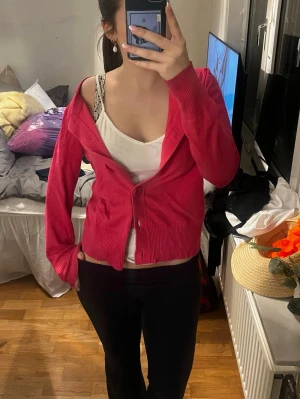 Rosa kofta med knappar - Snygg rosa kofta med stora knappar framtill och ribbade muddar vid ärmslut och nederkant. Koftan har en avslappnad passform och är perfekt att slänga över ett linne eller t-shirt. Inget synligt märke på plagget.