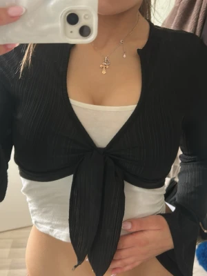 Svart bolerotopp med knyt  -  svart bolerotopp från Shein med långa ärmar och knyt framtill. Toppen är croppad och har ribbat material. Perfekt att styla över ett linne eller klänning 