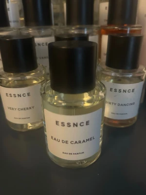 ESSNCE Eau de Caramel parfym - Obs FAST pris 200 kr, En stilren parfymflaska från ESSNCE med doften Eau de Caramel. Flaskan är genomskinlig med svart lock och vit etikett med minimalistisk text. Perfekt för dig som gillar söta och unika dofter. Glasflaskan ger en lyxig känsla och passar snyggt på hyllan.