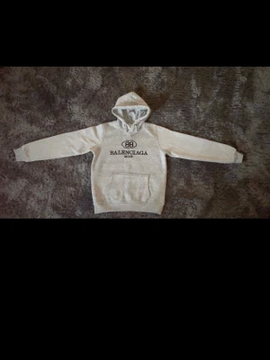 Grå hoodie  - En grå hoodie från BB med svart logotryck på bröstet och klassisk huva. Tröjan har en stor magficka och ribbade muddar vid ärmslut och nederkant. Perfekt för dig som gillar streetwear och exklusiva märken. Skriv gärna vid funderingar. Måtten på hoodien är: 54cm lång och 44cm bred