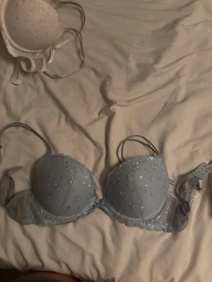 Ljusblå push-up bh med spetsdetaljer - Säljer en ljusblå push-up bh med fina broderade blommor och spetsdetaljer. Bh:n har justerbara axelband och bygel för extra stöd. Materialet är mjukt och bekvämt, perfekt för dig som vill ha något både snyggt och bekvämt.