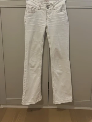 Vita bootcut jeans från Nelly - Säljer ett par vita bootcut jeans från Nelly med klassisk femficksdesign och dubbla silverknappar i midjan. Jeansen har utsvängda ben och är tillverkade i ett mjukt denimtyg med lite stretch. Perfekta för en trendig och fräsch look. Jeansen är upplagda, men är tillräckligt långa för nån som är 167cm. ❤️❤️
