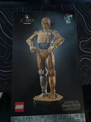 LEGO Star Wars C-3PO byggsats. Oöppnad pris kan diskuteras  - Byggsats från LEGO Star Wars-serien som föreställer C-3PO. Modellen är detaljerad med guldfärgade och silverfärgade delar, och står på en platta. Setet innehåller 1138 bitar och är rekommenderat för 18+. Perfekt för Star Wars-fans och samlare.