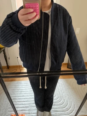 Mörkblå vårjacka med ränder - Snygg mörkblå vårjacka med vita tunna vertikala ränder och ribbade muddar. Supersnygg och trendig till våren! Storlek 40 men väldigt liten och kort i storleken💘 Pris är diskuterbart!
