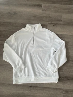 Vit halvzip hoodie - Snygg vit hoodie med halvzip och hög krage. Tröjan har långa ärmar, ribbade muddar och är tillverkad i ett mjukt material som känns skönt mot huden. Perfekt för en clean och stilren look. Jag vet tyvärr inte märke eller storlek då det inte står. Jag uppskattar S/M. Endast testad!