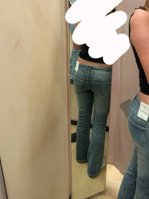 Bootcut jeans i ljusblå denim - Säljer ett par snygga bootcut jeans i blå tvätt med låg midja och klassiska fem fickor. Jeansen har en lätt slitning och är tillverkade i stretchig denim för skön passform. Perfekta för dig som gillar lågmidjade jeans.
