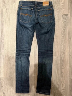 Nudie Jeans Tight Long John Denim Stretch W30/L34 Slim Fit - Nudie Jeans Tight Long John i blå denim med stretch, slim fit modell som sitter bra och funkar till allt, storlek W30/L34, midja 40 cm, ytterbenslängd 107 cm, benöppning 16 cm, modellen är 185cm & väger 65kg, i fint skick.