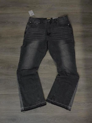 Mörkgrå jeans från Jack & Jones - Säljer ett par mörkgrå jeans från Jack & Jones med klassisk femficksdesign och rå, fransad nederkant. Jeansen har normal passform och är tillverkade i bomull. Perfekta för dig som gillar en avslappnad och cool stil.