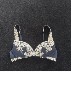 Intimissimi bh - Snygg mörkblå bh från intimissimi med vadderade kupor och vacker beige spetsbrodyr över kupor och axelband. Bh:n har justerbara axelband och hakknäppning bak. Materialet är en kombination av mesh och spets som ger en lyxig känsla.