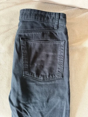 Svarta raka jeans - Säljer ett par svarta jeans med rak passform och klassisk femficksdesign. Jeansen har normal midja och är tillverkade i ett kraftigare denimtyg. 