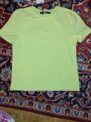 Ljusgul t-shirt från BikBok - En enkel och fräsch ljusgul t-shirt från BikBok i storlek M. T-shirten har klassisk rund halsringning och korta ärmar. Tillverkad i mjuk bomull som känns skön mot huden. Perfekt att matcha med jeans eller kjol för en clean look.