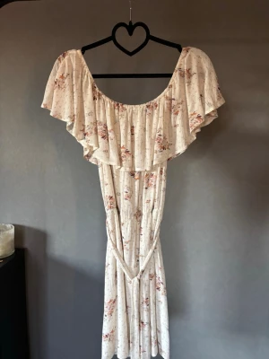 Blommig långklänning med volang - Perfekta sommarklänningen! Luftig och skön med en fin knytdetalj i midjan 💞 går att ha både off shoulder och som vanligt, dubbelt kjol-tyg! 