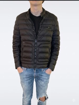 Belstaff Jacka Herr - M  - Säljer en riktigt stilren lättviktsjacka från premiummärket Belstaff. En perfekt jacka med en modern som sitter riktigt snyggt på.  Storlek: 46  Passform: Modellen på bilden är 177 cm lång och väger ca 68 kg.  Skick: Jackan är använd och har några mindre hål som har blivit fint lagade och ihopsydda. Det är inget som stör helhetsintrycket, men det gör att du kan fynda en premiumjacka till ett riktigt bra pris!