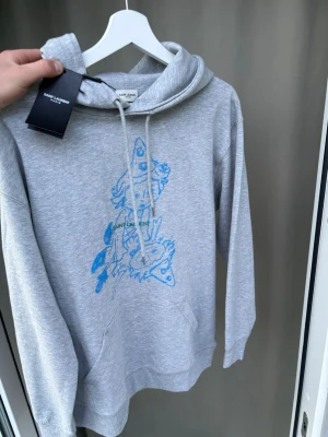 Saint Laurent hoodie - Ny saint Laurent hoodie med tags kvar. Storlek L, sjukt snygg med basic stilrent tryck som passar till varenda dags bruk. Hör av er vid frågor! 