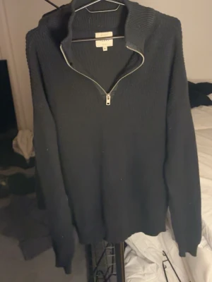 Svart stickad tröja med halv dragkedja - Svart stickad tröja från Arket med hög krage och halv dragkedja framtill. Tröjan har lång ärm och är tillverkad i ett grovstickat material som ger en avslappnad och stilren look. M men passar L med