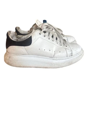 Alexander Mcqeen sneakers - Stilrena vita sneakers med svart detalj på hälen och tjock sula. Välanvända med slitningar.