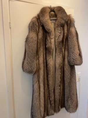 Pälskappa  - Otrolig vintage kappa med fantastisk kvalitet och vackra naturliga färgskiftningar. Klassisk lång modell med generös,fyllig och mjuk sjalkrage.  Kappan är varm, stor, lyxig och har ett mycket fint fall.    • Lång modell • Elegant sjalkrage • Fodrad insida • Vackra naturliga nyanser i silver/grå/brunt • Fint vintage-skick
