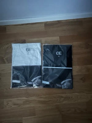 Svart och vit t-shirt från CE - stilren Avicii t-shirt från CE, finns  i vitt och i svart, båda med tryck och rund hals. T-shirtsen har en modern design med grafiskt motiv och logga på bröstet. Perfekt för dig som gillar streetwear och enkel stil. Och grisch!