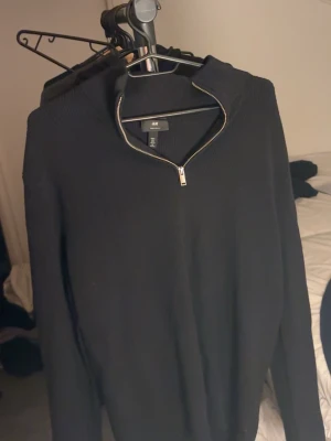 Svart halvzip-tröja  - Svart stickad tröja från H&M med halvzip och hög krage. Tröjan har lång ärm och är tillverkad i ett mjukt material som passar perfekt till lager-på-lager. Enkel och stilren design som funkar till det mesta. passar L också