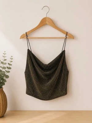 Glittrig linne-topp från H&M Divided - Snygg glittrig linne-topp från H&M Divided med tunna svarta axelband och draperad halsringning. Toppen har en mörk bas med guldglittriga detaljer och är perfekt för att sticka ut. Materialet är mjukt och följsamt.