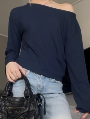 Mörkblå offshoulder långärmad topp nelly - Trendig mörkblå offshoulder topp med lång ärm och avslappnad passform. Perfekt att styla med jeans för en cool och enkel look. Mjuk och skön mot huden.