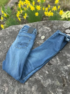 Replay Jeans - Anbass - Snygga blå jeans från Replay Jeans med klassisk femficksdesign och diskreta slitningar. Jeansen har en smal passform och normal midja. Perfekta för dig som gillar en stilren och tidlös look. Materialet är mjukt och stretchigt för extra komfort.