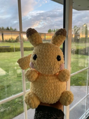 Virkad Pikachu med baby rosa kinder - Supergullig handvirkad Pikachu. Gjord i mjukt, gult garn med svarta ögon, baby rosa kinder och har alla bruna detaljer. Perfekt som prydnad eller gosedjur. Kan även passa som en present till en riktig pokemon älskare