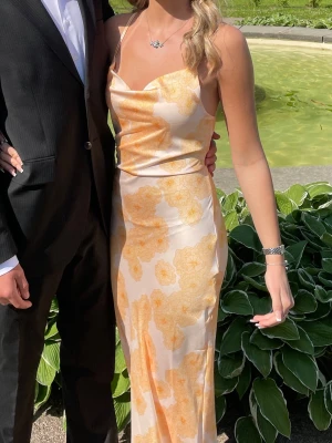 Balklänning - Jättefin balklänning i orange/gul och vit satin med blommigt mönster. Klänningen är öppen i ryggen. Jag är 167 cm och den är lagom i längden på mig. 