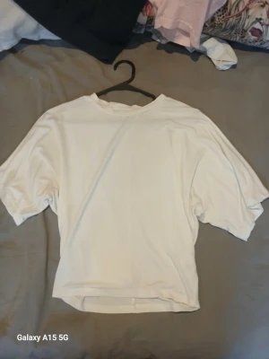 Vit t-shirt från 157 i bomull - En basic vit t-shirt från 157 i storlek XS. T-shirten har korta ärmar och en klassisk rund halsringning. Perfekt att matcha med jeans eller shorts för en enkel och clean look.