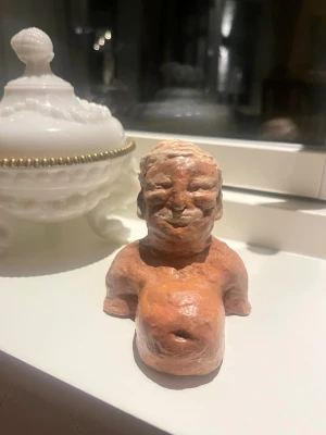 Gravida Trump - Unik handgjord byst i rödbrun lera som föreställer en person med markerat ansikte och överkropp. Skulpturen har en rustik och konstnärlig känsla, perfekt som dekoration eller samlarobjekt.